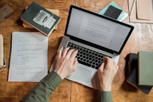 Copywriting for Small Businesses: Small business owner writing marketing copy on a laptop with a notebook and coffee on the desk